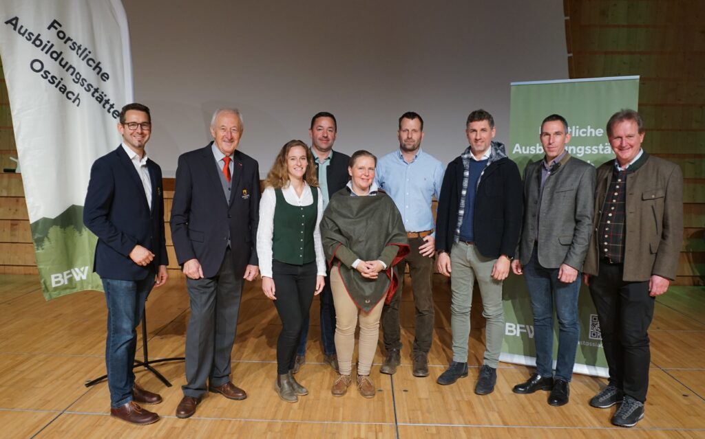 Es stehen mehrere Personen aufgereihtauf einer hölzernen Bühne.