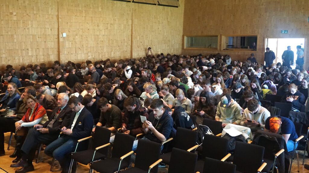 Viele Schüler sitzen und schauen auf ihr Handy.